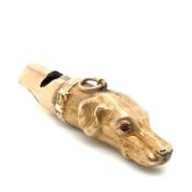 AN ANTIQUE HUNTING DOGS HEAD WHISTLE SET WITH RUBY RED CABOCHON EYES. UNHALLMARKED, ASSESSED AS