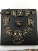 A MULTI PANEL NECKLACE, BRACELET AND RING SUITE. THE PANELS DEPICTING FIGURES IN VARIOUS SCENES.