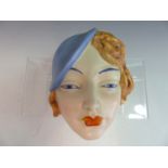 AN ART DECO POTTERY WALL MASK OF A YOUNG WOMAN WITH BLUE HAT. PROBABLY BY BESWICK. IMPRESSED MARKS