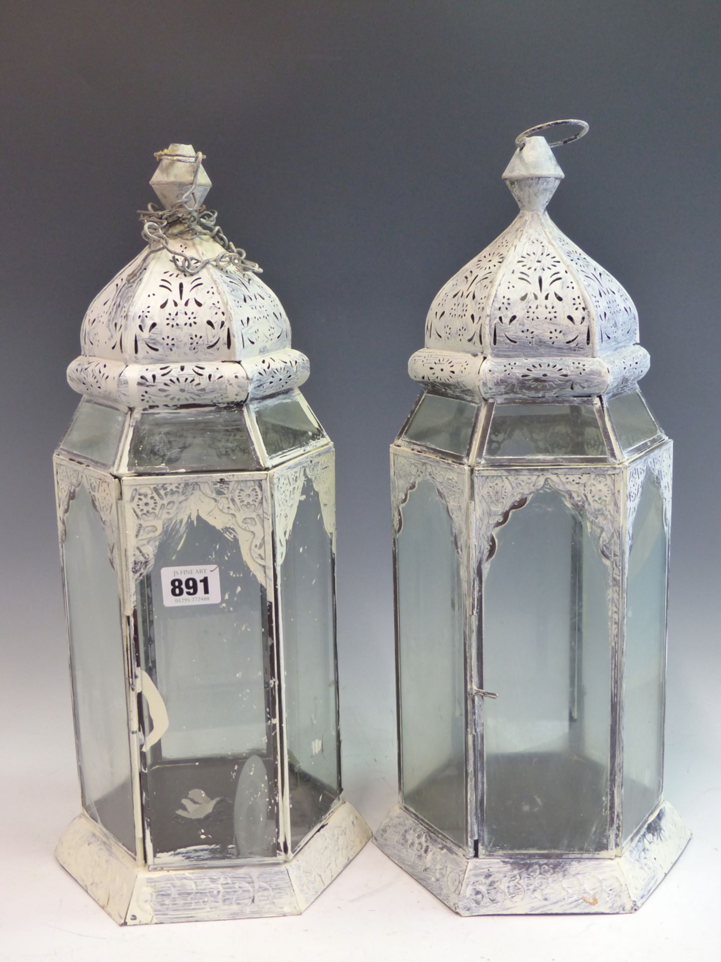 A PAIR OF PAINTED HEXAGONAL PIERCED METAL AND GLASS HANGING CANDLE LANTERNS.