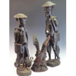 TWO AFRICAN HARDWOOD STANDING FIGURES, A PAIR OF HEADS, A RELIEF CARVED PLAQUE, A TABLE LAMP PIERCED