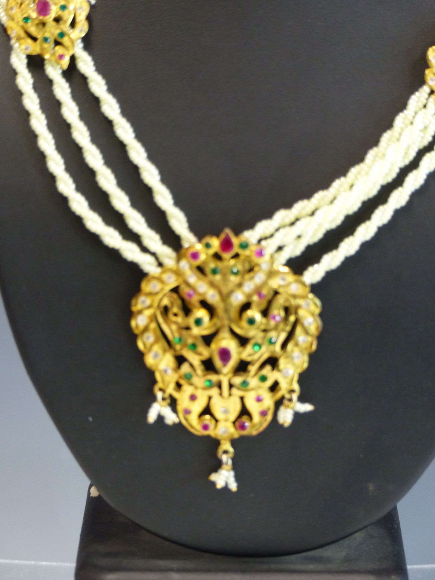 AN EASTERN NECKLACE THE GILDED PENDANT SET WITH COLOURED PASTE STONES SUSPENDED ON A WOVEN PEARL - Image 2 of 3