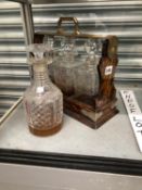 AN OAK CASED THREE BOTTLE TANTALUS TOGETHER WITH A CUT GLASS DECANTER