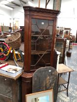 A FLOOR STANDING CORNER CABINET.