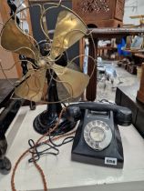 A VINTAGE BRASS AND IRON FAN AND A BAKELITE TELEPHONE.