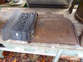 AN ANTIQUE CAST IRON STOVE DOOR AND A FREE STANDING FIRE FRONT BAR.