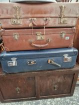 THREE VINTAGE SUIT CASES AND AN OTTOMAN.
