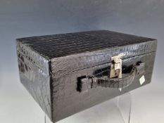 A BLACK CROCODILE JEWELLERY CASE OF SUIT CASE FORM LINED IN TERRACOTTA TEXTILE. W 29cms.