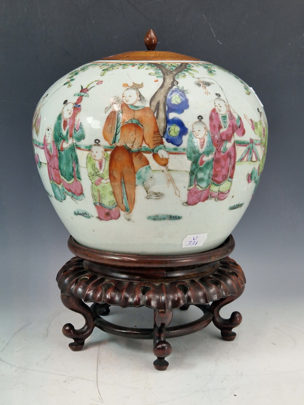A CHINESE FAMILLE VERT SQUAT FORM JAR DECORATED WITH FAMILY SCENE. AND STANDING ON A CARVED WOODEN