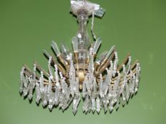A CHANDELIER WITH LIGHTS ABOVE SICKLE SHAPED ARMS HUNG WITH PRISMATIC DROPS