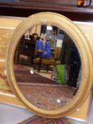 AN OVAL MIRROR IN A GILT FRAME WITH BEAD AND GUILLOCHE BANDS. 95 x 79cms