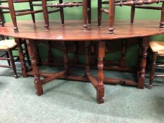 AN OAK WAKE TABLE, THE OVAL FLAP TOP ON BALUSTER LEGS JOINED AT THE SQUARE SECTION FEET BY