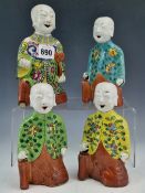FOUR 19th C. CHINESE FIGURAL JOSTICK HOLDERS EACH WITH FLORAL JACKETS AND RED TROUSERS, THE TALLEST.