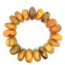 A LARGE AMBER EXPANDING BRACELET OF 19 IRREGULAR SHAPED ROUNDLES. GROSS WEIGHT 92.46grms.