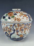 AN 18th C. JAPANESE IMARI BOWL AND COVER PAINTED WITH FLOWERING SHRUBS, TREES AND WITH