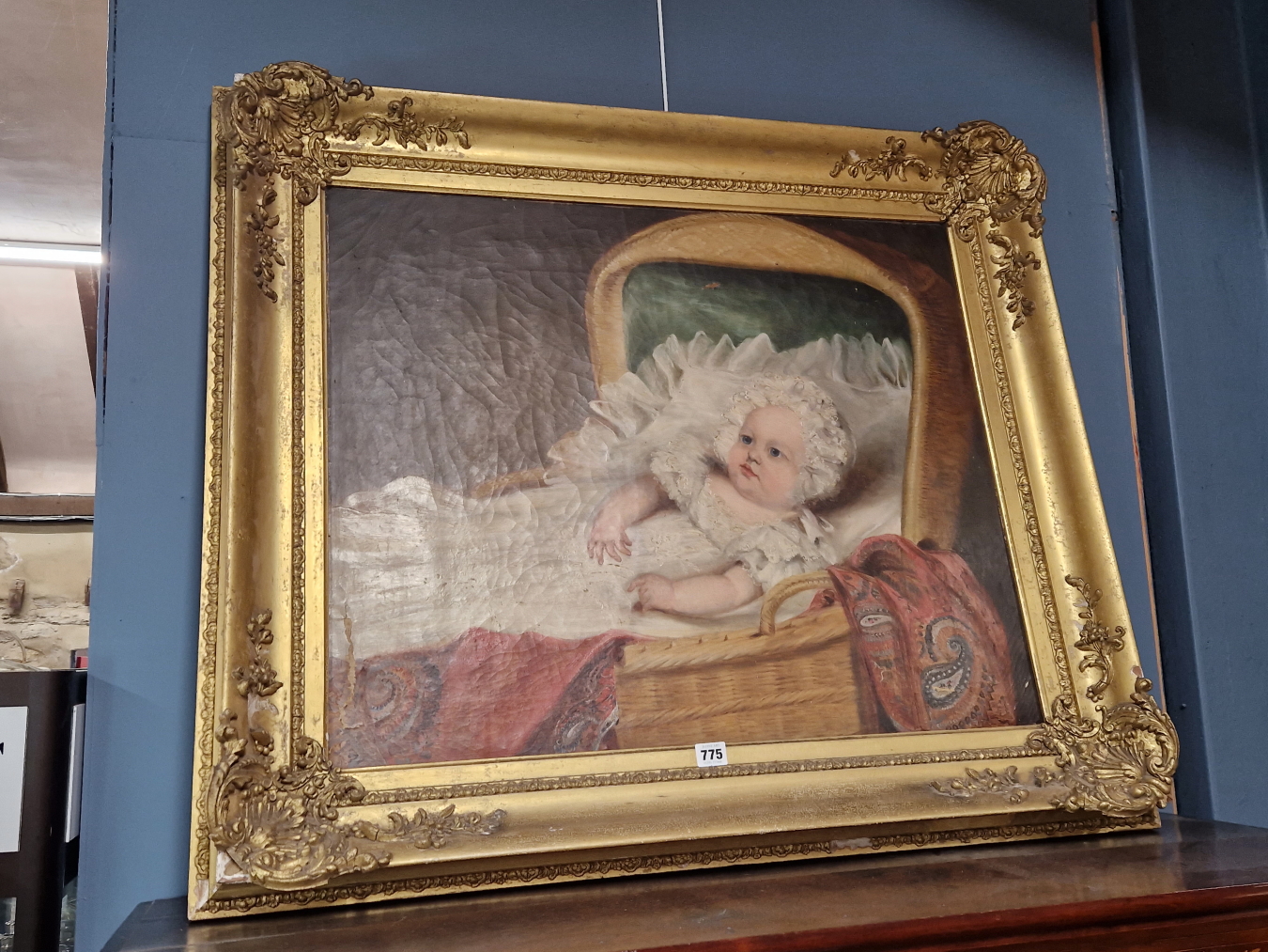 VICTORIAN SCHOOL, A BABY IN ITS BASKET WARE COT, OIL ON CANVAS. 64 x 76cms.