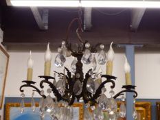 A SIX LIGHT CANDLE FORM CHANDELIER, EACH HUNG WITH A BEAD ABOVE A PEAR SHAPED DROP FROM FOLIATE