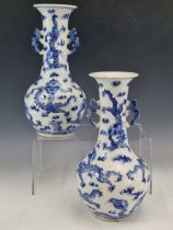 A PAIR OF CHINESE BLUE AND WHITE TWO HANDLED BOTTLE VASES PAINTED WITH DRAGONS AMONGST CLOUDS AND