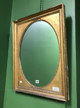 AN OVAL MIRROR IN A GILT RECTANGULAR FRAME WITH BEADED BANDS. 68 x 54cms.