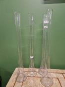 FOUR SLENDER GLASS VASES ON CIRCULAR FEET. H 80cms.