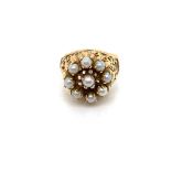 A PEARL CLUSTER RING. THE NINE PEARLS EACH IN A FOUR CLAW SETTING ON A RAISED FILIGREE AND PIERCED
