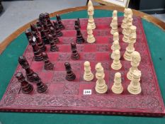 A BROWN AND CREAM COMPOSITION CHESS SET ON A RED BOARD, THE KINGS. H 16cms.