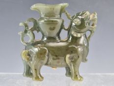 A CHINESE GREEN HARDSTONE QILIN AND WOOD STAND, THE MYTHICAL BEAST STANDING BEARING A VASE ON ITS
