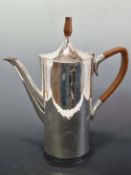 A SILVER COFFEE POT BY D J L, LONDON 1987, THE HAMMERED BODY OF OVAL SECTION WITH A WOODEN HANDLE