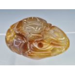 A CHINESE MOTTLED BROWN AGATE PEBBLE PIERCED AND CARVED WITH AN ANIMAL COILED AMONGST CASH. W 7cms.