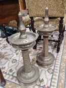A PAIR OF SILVERED METAL PRICKET CANDLESTICKS WITH DISHED DRIP PANS AND CIRCULAR FEET, THE COLUMNS