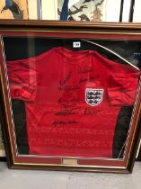 1966 ENGLISH FOOT BALL: A FRAMED RED SHIRT SEWN WITH THE ENGLAND BADGE AND SIGNED IN BLACK BY TEN