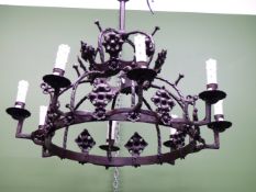 AN IRON CROWN WHEEL SHAPED CEILING LIGHT, THE EIGHT CANDLE FORM LIGHTS ALTERNATING WITH GOTHIC