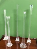 A SET OF FOUR SLENDER GLASS VASES ON SQUARE SECTIONED BUTTRESS FEET. H 80cms.