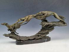 A BRONZE GROUP OF THREE GREYHOUNDS RACING OVER ROUGH GROUND. W 53cms.