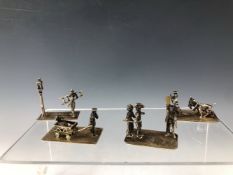 FOUR WHITE METAL MINIATURES DEPICTING SKATERS, A CHILD DRAWN IN A CARTS, A LED GOAT AND A STREET