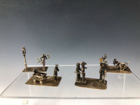 FOUR WHITE METAL MINIATURES DEPICTING SKATERS, A CHILD DRAWN IN A CARTS, A LED GOAT AND A STREET