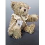 A STEIFF TEDDY BEAR WITH PALE SHAGGY FUR AND WEARING A LACE COLLAR. H 27cms.