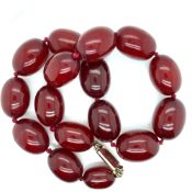 A ROW OF GRADUATED CHERRY RED AMBER BEADS TOGETHER WITH A FURTHER STRAND OF YELLOW AMBER BEADS