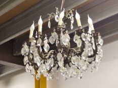 A CHANDELIER WITH TEN CANDLE FORM LIGHTS HUNG WITH DIAMOND SHAPED DROPS FROM FOLIATE SCROLLING ARMS