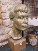 A BRONZE PATINATED PLASTER BUST OF A LADY WITH HER HAIR DRESSED IN A BUN. H 47cms.