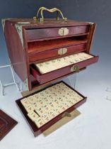 A WOODEN CASED BONE AND BAMBOO MAHJONG SET, THE BRASS MOUNTED CASE. W 24cms.