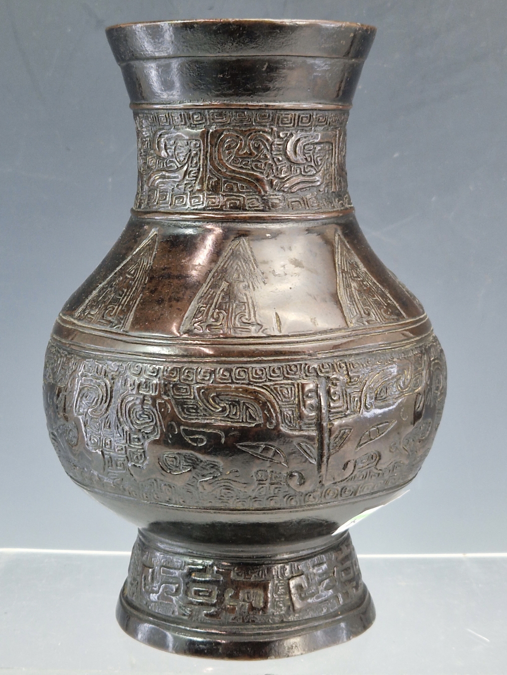 A CHINESE BRONZE BALUSTER VASE CAST WITH BANDS OF DAODIEH AND WITH CHEVRON LAPPETS ON THE SHOULDERS.