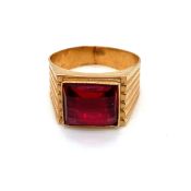A RED CHEQUERBOARD CUT SYNTHETIC RUBY SET IN A SIGNET STYLE RING MOUNT. UNHALLMARKED, CROWN AND