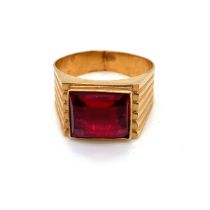 A RED CHEQUERBOARD CUT SYNTHETIC RUBY SET IN A SIGNET STYLE RING MOUNT. UNHALLMARKED, CROWN AND