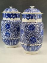 A PAIR OF CHINESE BLUE AND WHITE VASES AND COVERS PAINTED WITH LOTUS FLOWERS AMONGST THEIR TIGHTLY