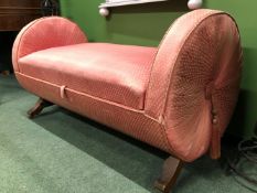 A DIAPERED PINK UPHOLSTERED OTTOMAN, THE ROUND ENDS CENTRED BY TASSELS AND FLANKING THE SEAT LID