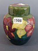 A MOORCROFT GREEN GROUND ANEMONE PATTERN JAR AND COVER, LABEL AND IMPRESSED MARK