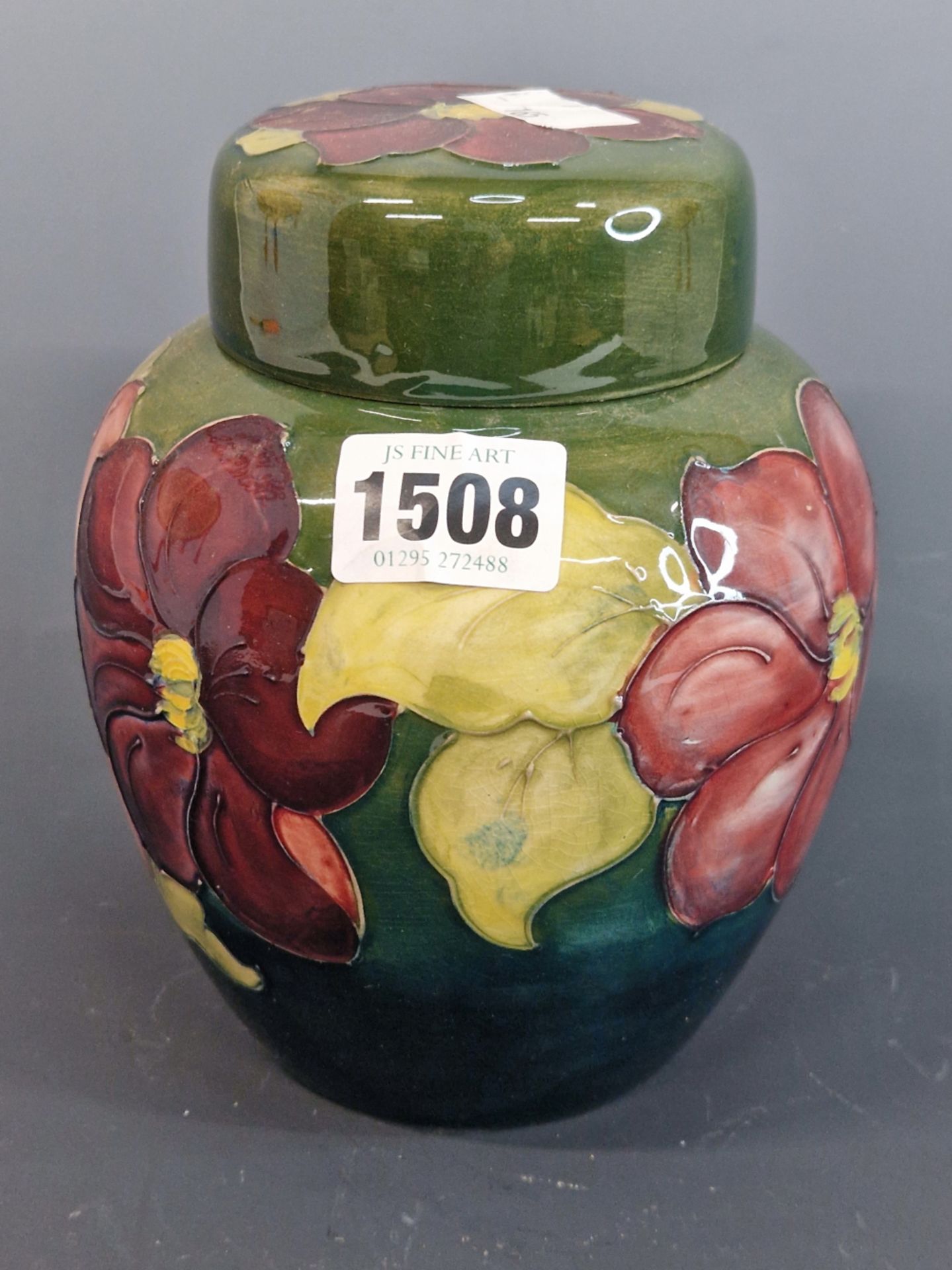 A MOORCROFT GREEN GROUND ANEMONE PATTERN JAR AND COVER, LABEL AND IMPRESSED MARK