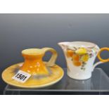 A SHELLEY TONED ORANGE CHAMBER STICK TOGETHER WITH A CREAM JUG WITH ORANGE AND YELLOW DAISIES