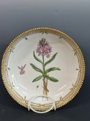 A ROYAL COPENHAGEN BOTANICAL SHALLOW BOWL PAINTED WITH AN ORCHID WITHIN THE GILT SERRATED RIM.